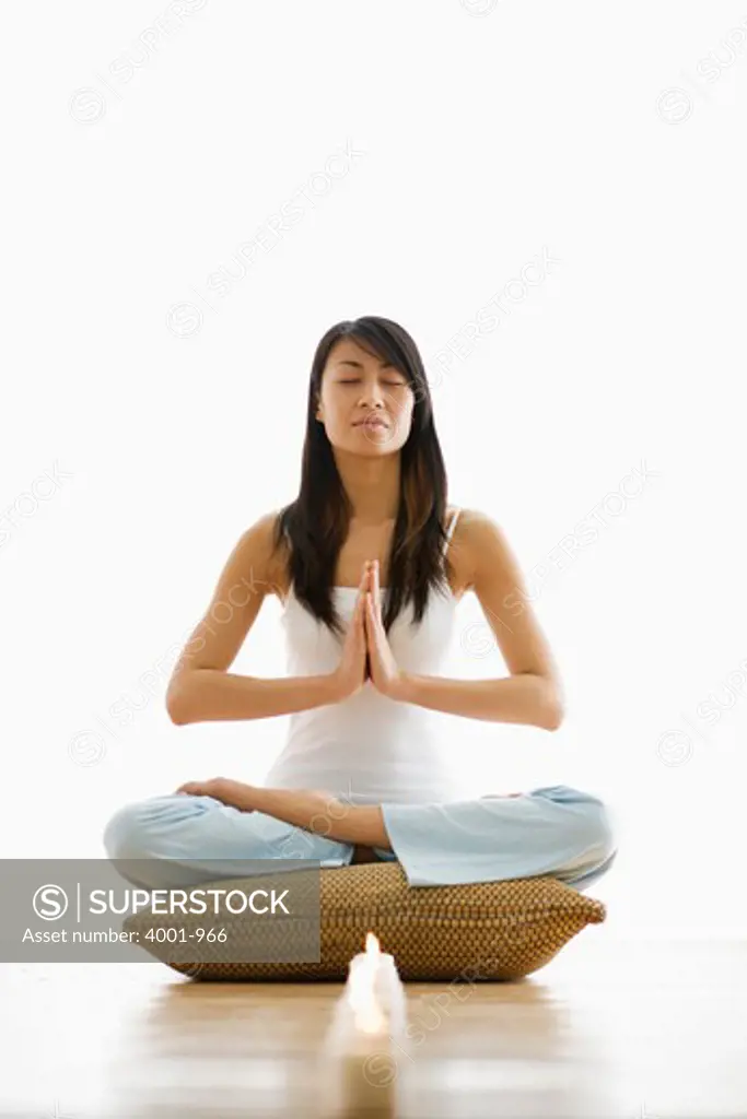 Young woman meditating with lit candles in front of her