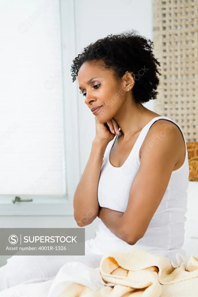 Mid adult woman sitting on the bed and thinking