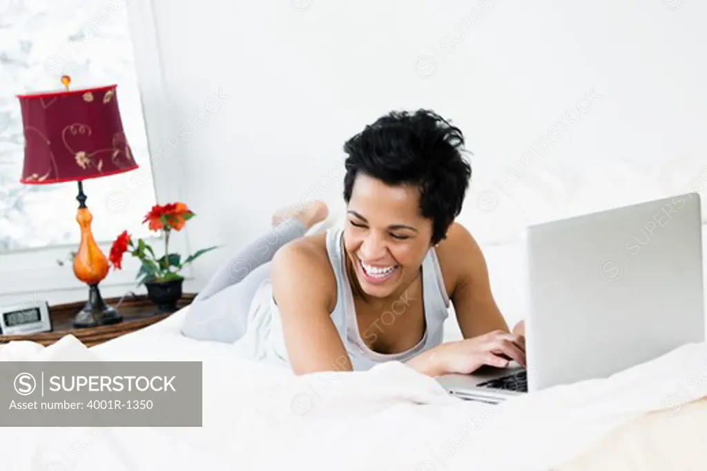 Mid adult woman using a laptop on the bed