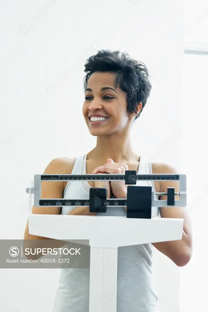 Mid adult woman measuring her weight on a weighing scale