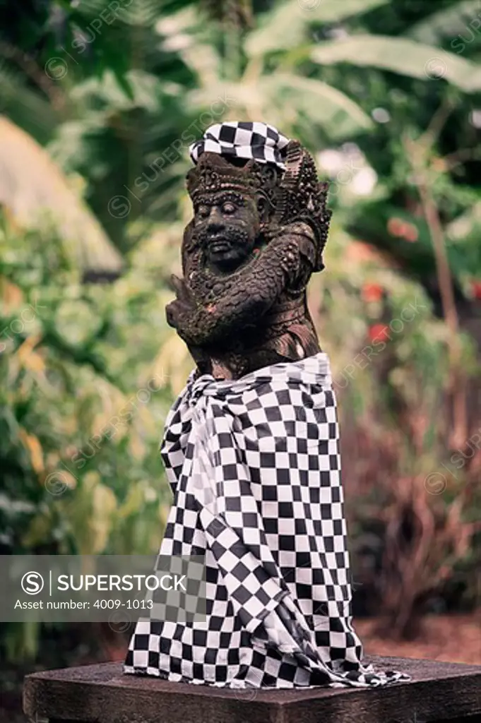 Statue of a warrior wearing a checkered skirt in the forest, Bali, Indonesia