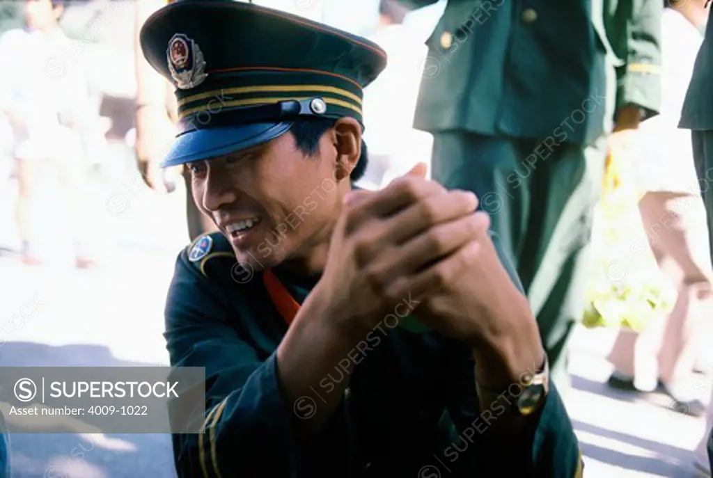 Chinese soldier laughing while clasping his hands together, China