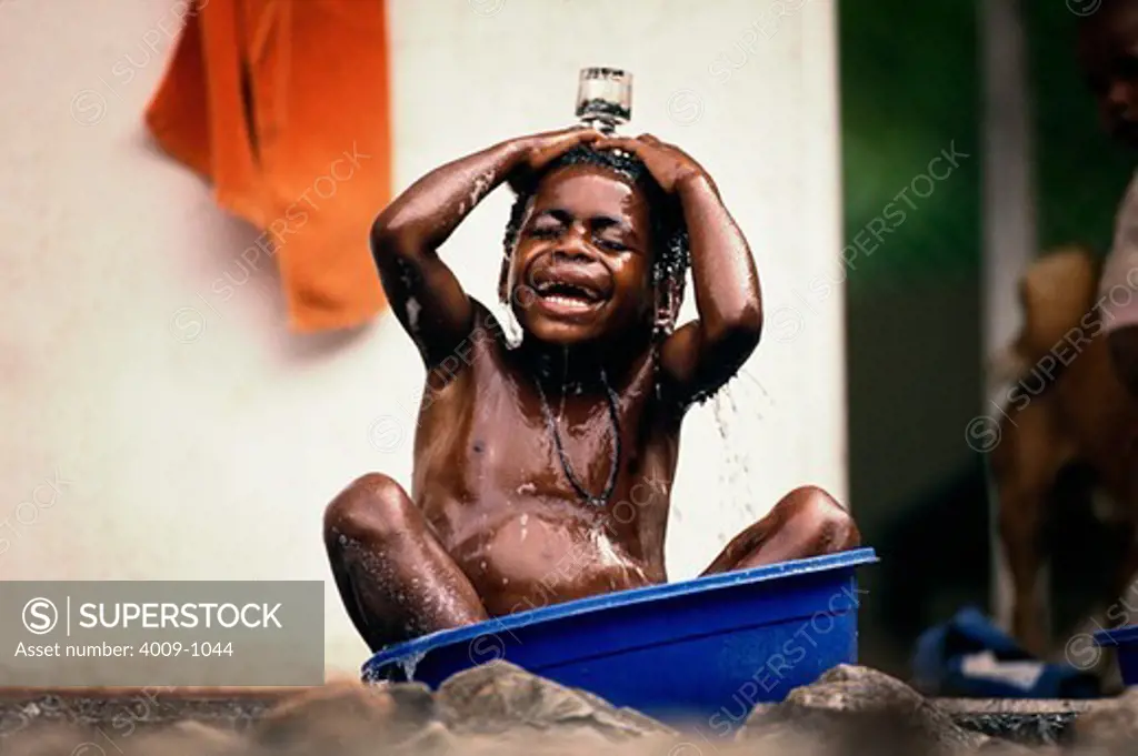 Indonesian boy bathing in a blue bucket, Irian Jaya, New Guinea, Indonesia