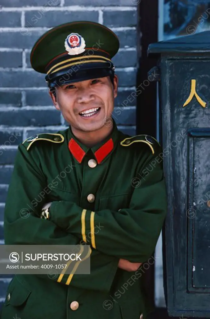 Portrait of a smiling Chinese soldier in uniform standing with his arms crossed, China