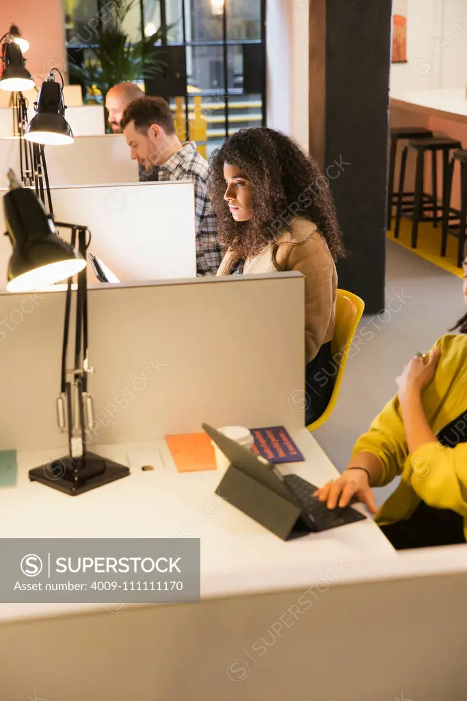 group of young adults at individual workstations in co-working space