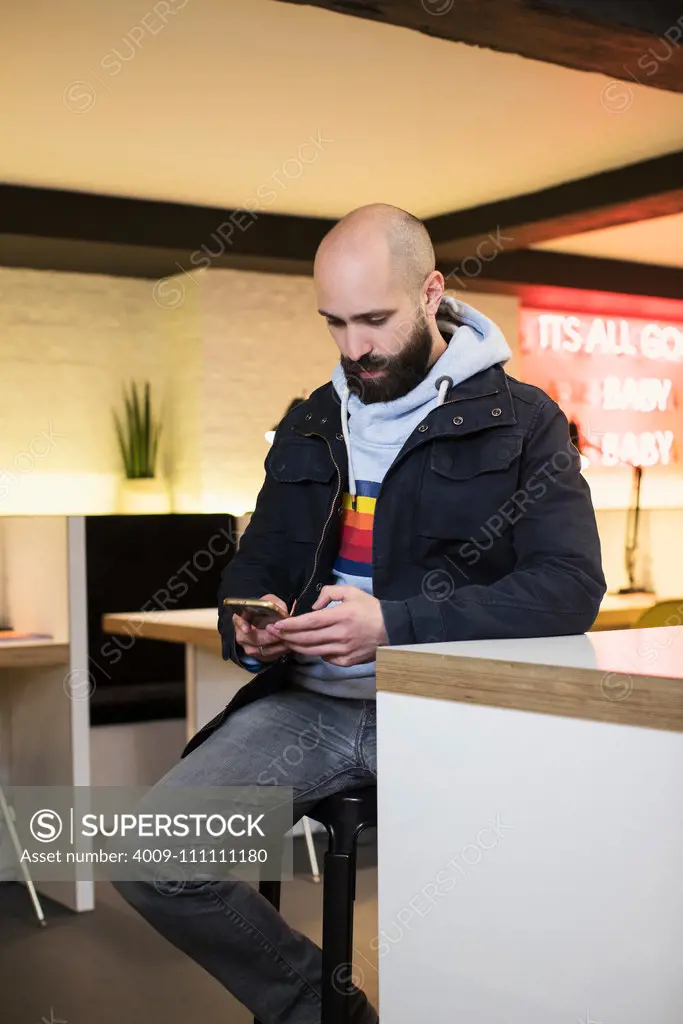 Man checking his phone while sitting at table in co-working space
