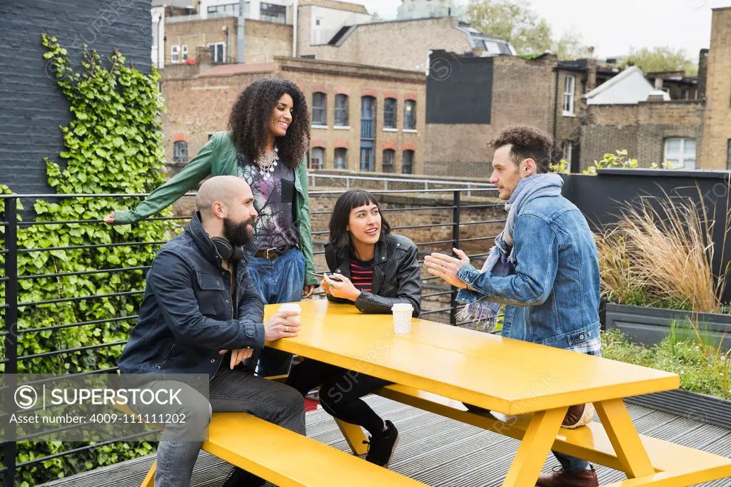 Group of friends working on tablets at outdoor patio table in co-working space