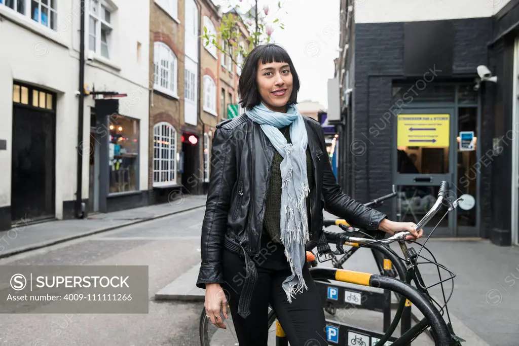 Portrait of Woman parking bicycle on sidewalk