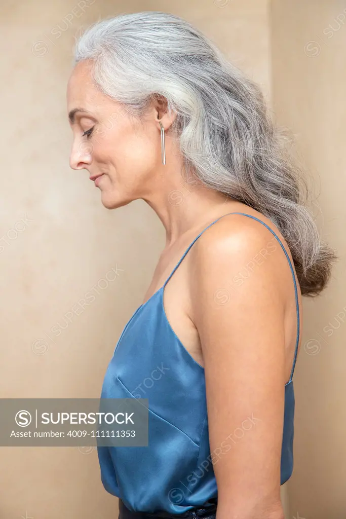Profile portrait of a middle-aged woman with grey hair looking down with her eyes closed.