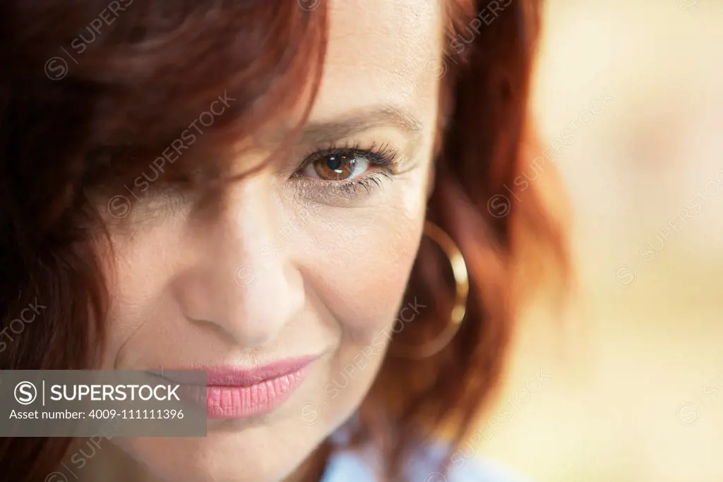 Close up portrait of woman with red hair, chin down looking into to camera.