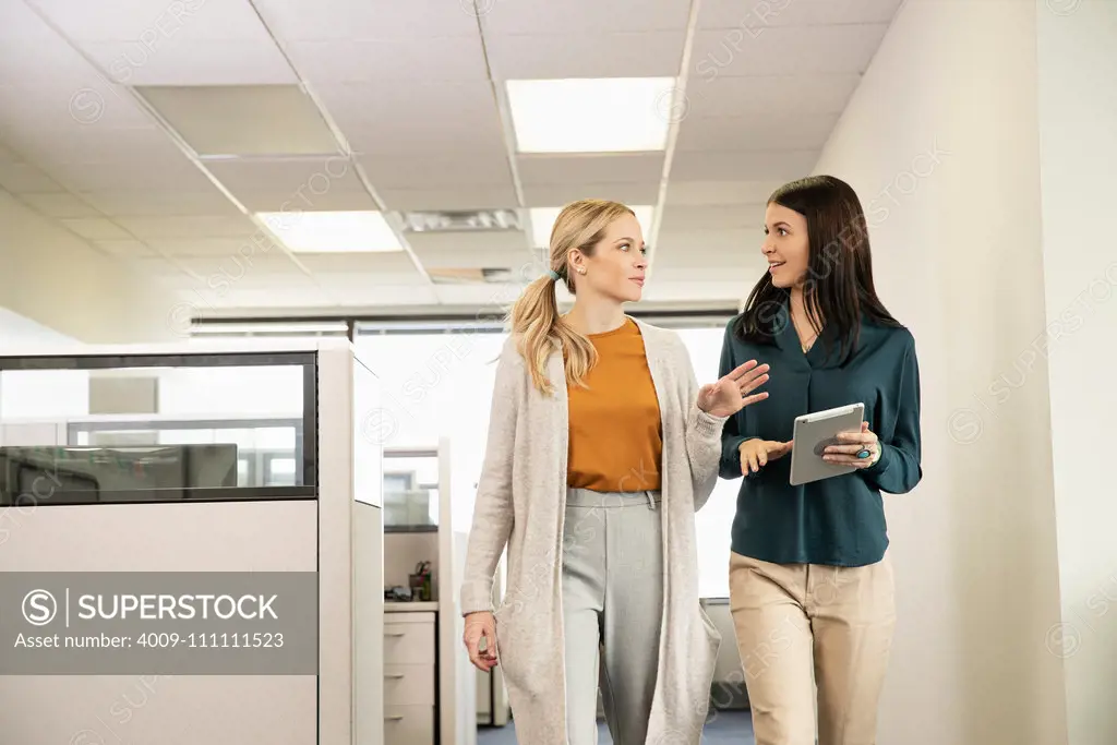 Two co-workers walking together in an office