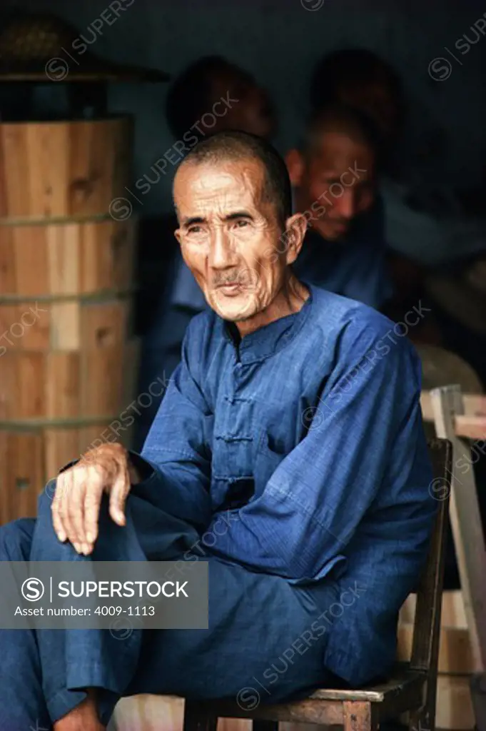 Man sitting on a chair with his legs crossed, China
