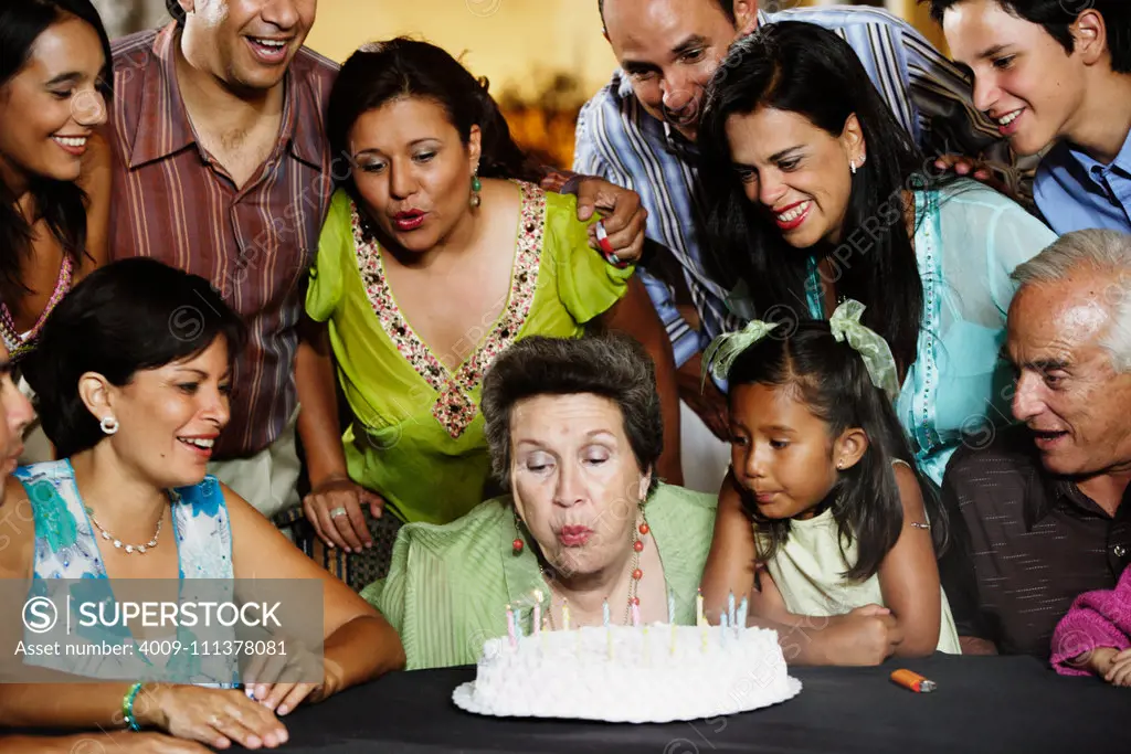 Senior woman blowing out the candles on her birthday cake