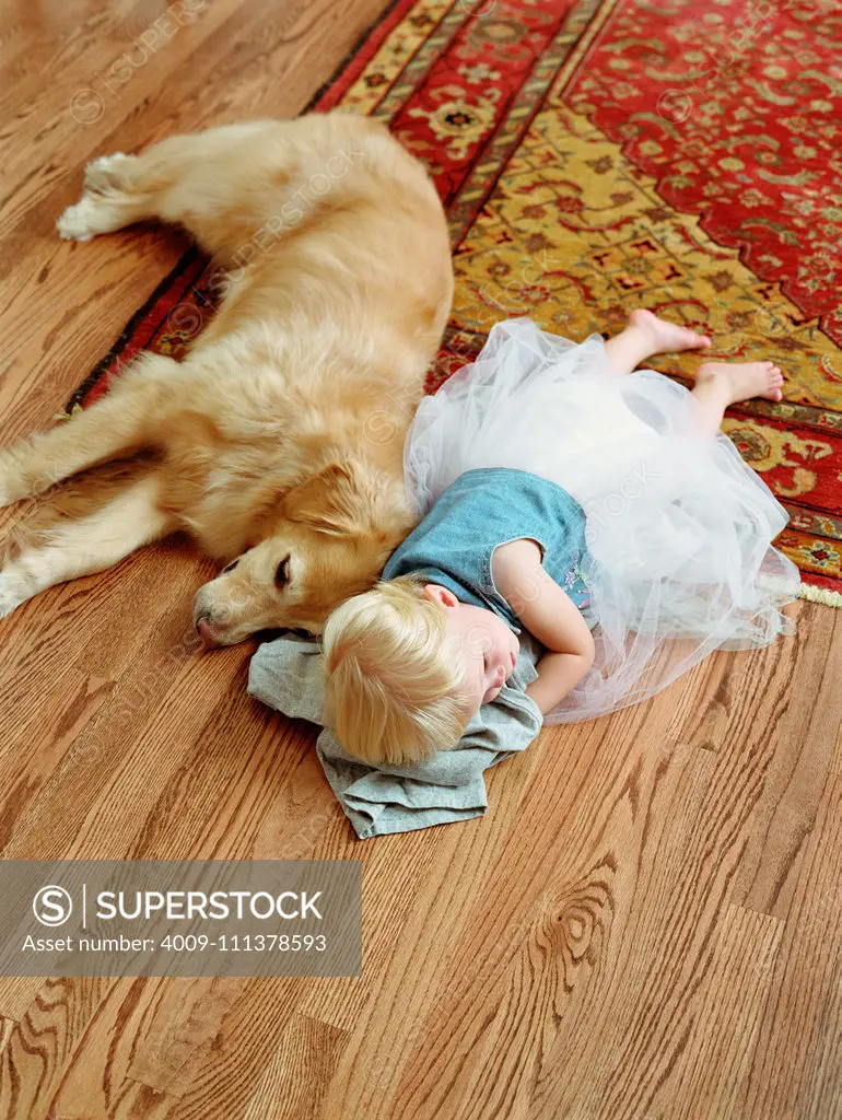 Toddler girl laying on floor with dog