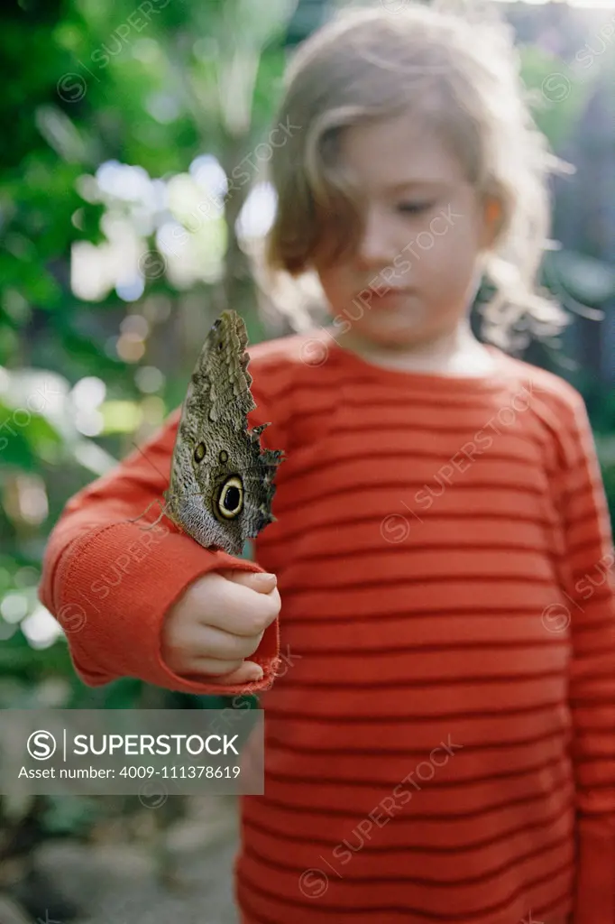 Young girl with butterfly on arm outdoors