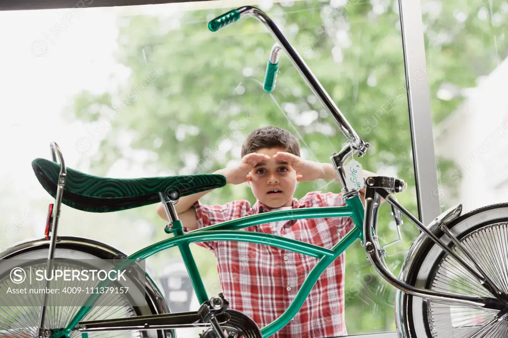 Boy looking at bike through store window