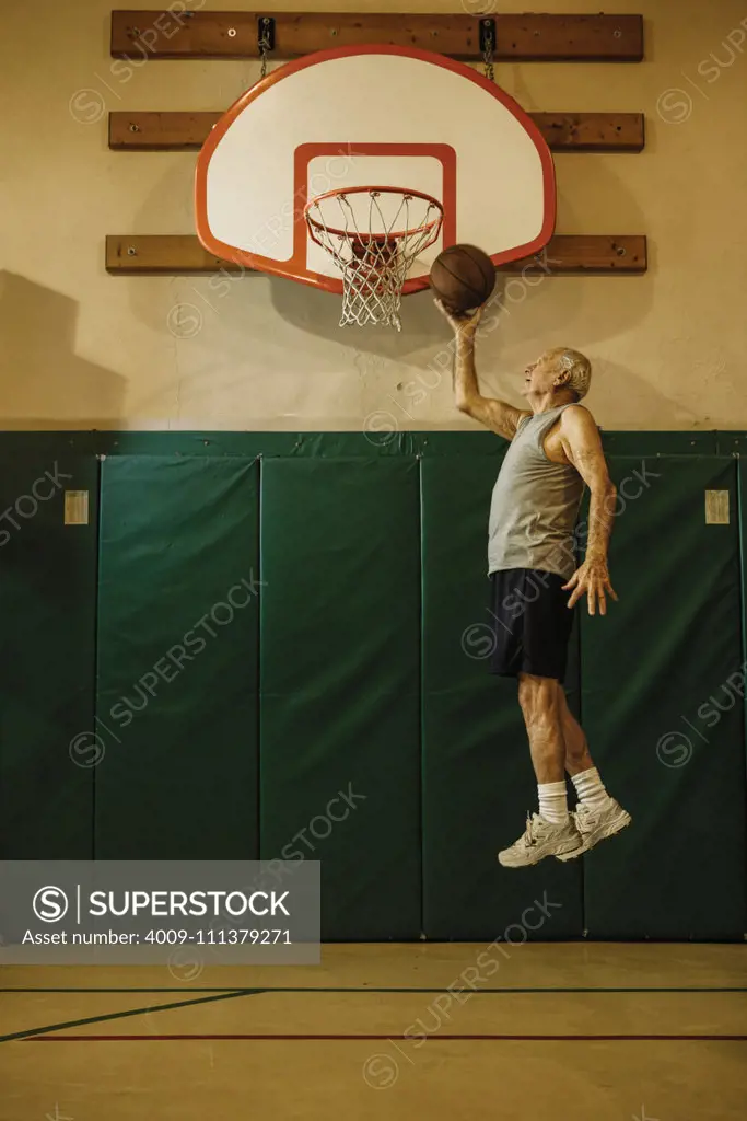 Elderly men jumping to slam dunk a basketball