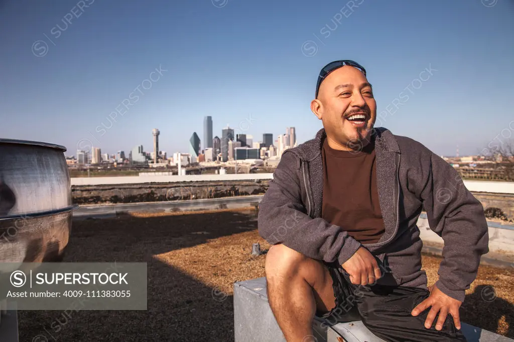 Laughing man sitting on rooftop
