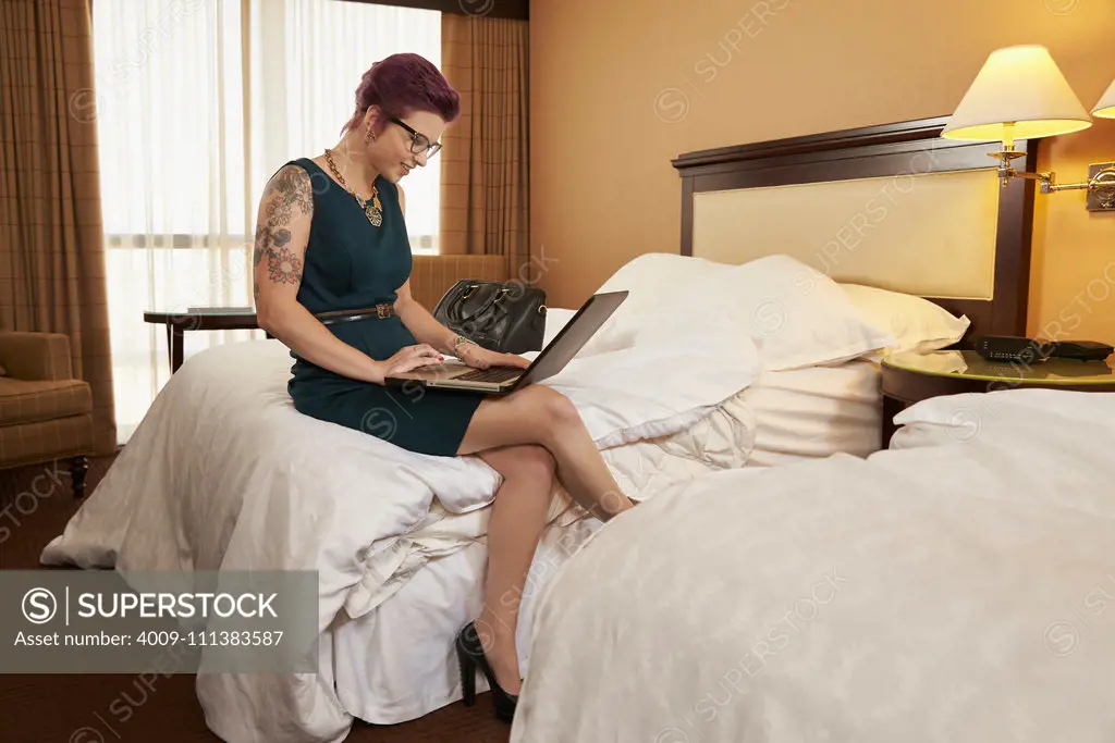 Caucasian woman using laptop on hotel bed