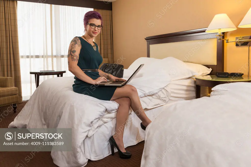 Caucasian woman using laptop on hotel bed