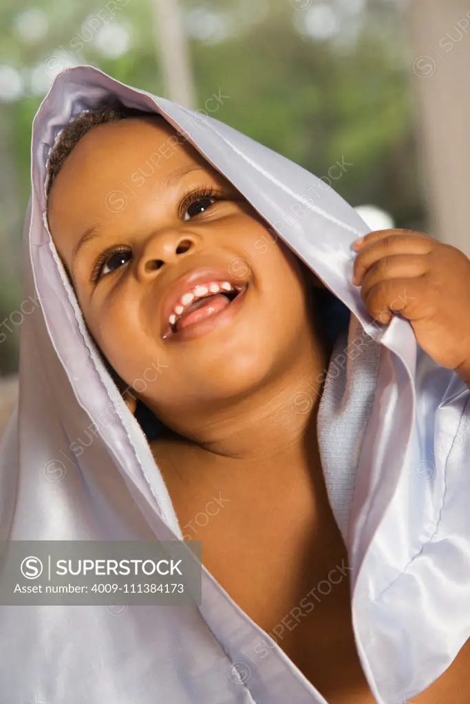 Smiling Black boy covered with blanket