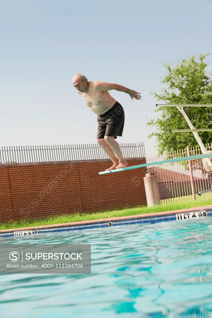 Senior Hispanic man diving off board into swimming pool
