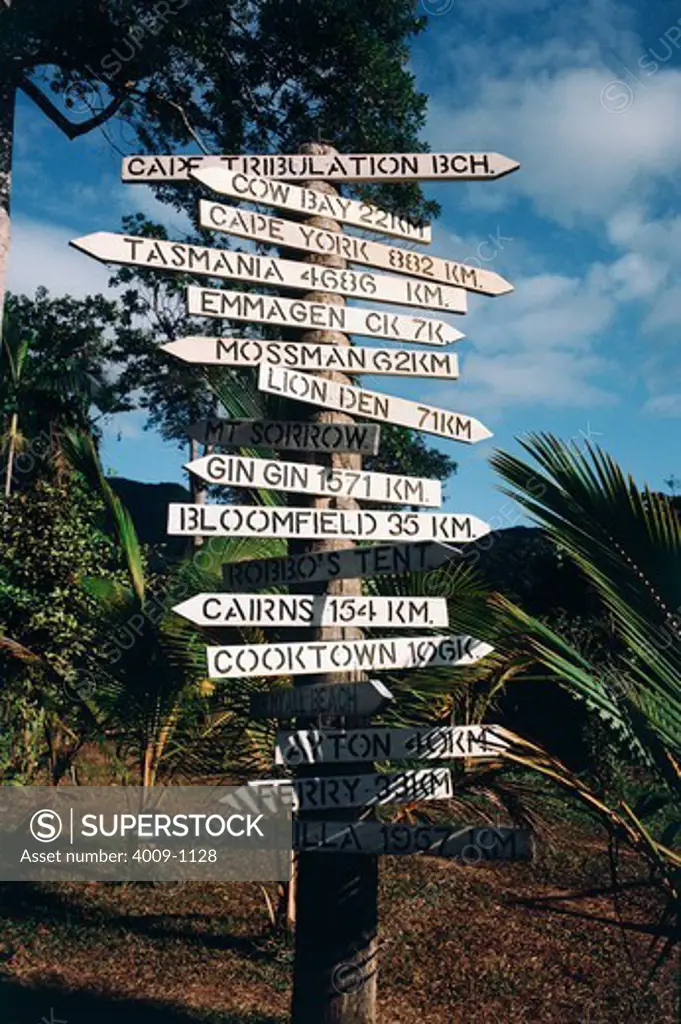 Directional signs posted to a pole surrounded by lush plants, Port Douglas, Queensland, Australia