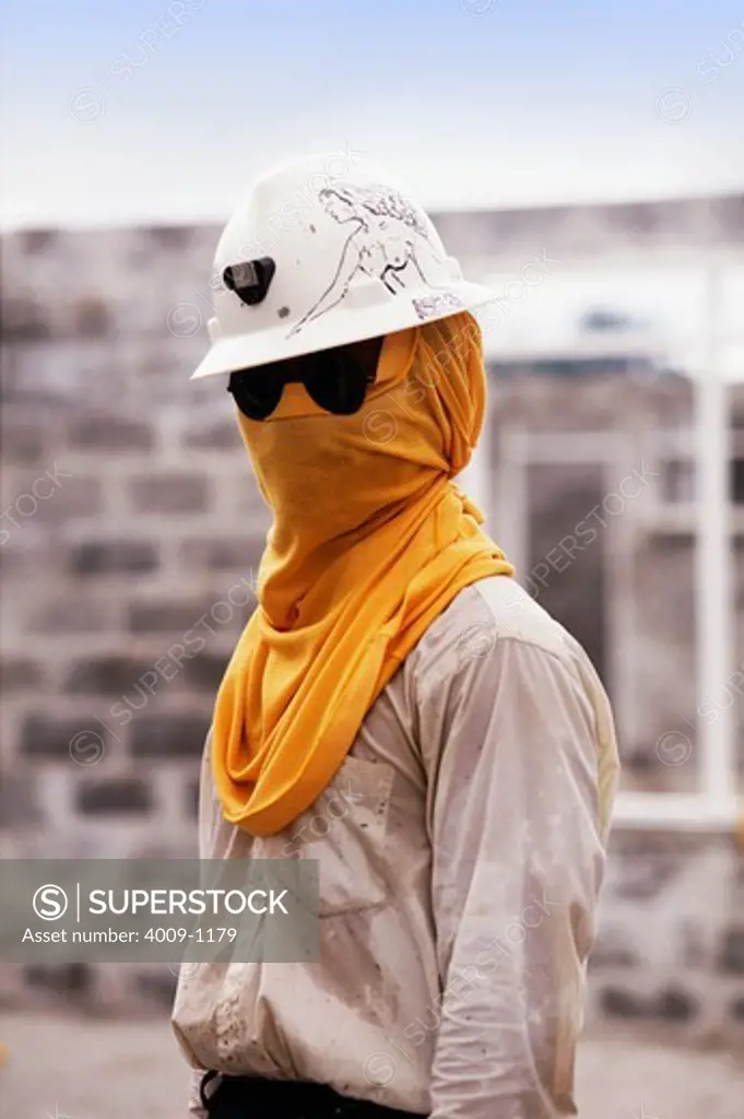 Man wearing hard hat decorated with drawing of a woman with sunglasses and yellow cloth over his face for protection during mining, Irian Jaya, New Guinea, Indonesia