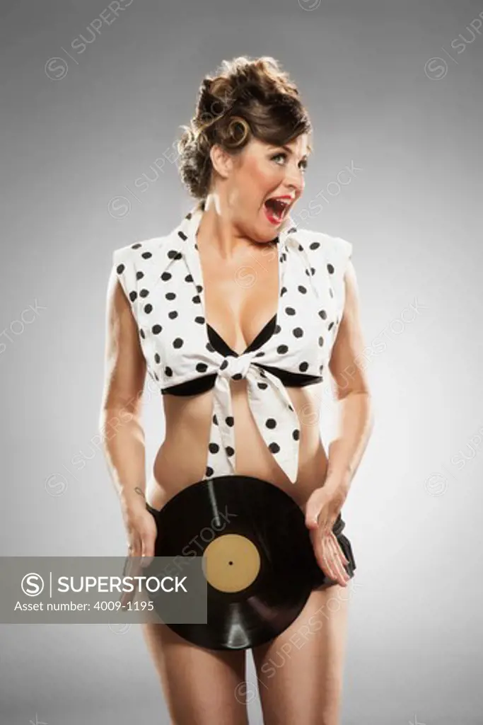 Portrait of tattooed pin-up girl in studio holding vinyl albums