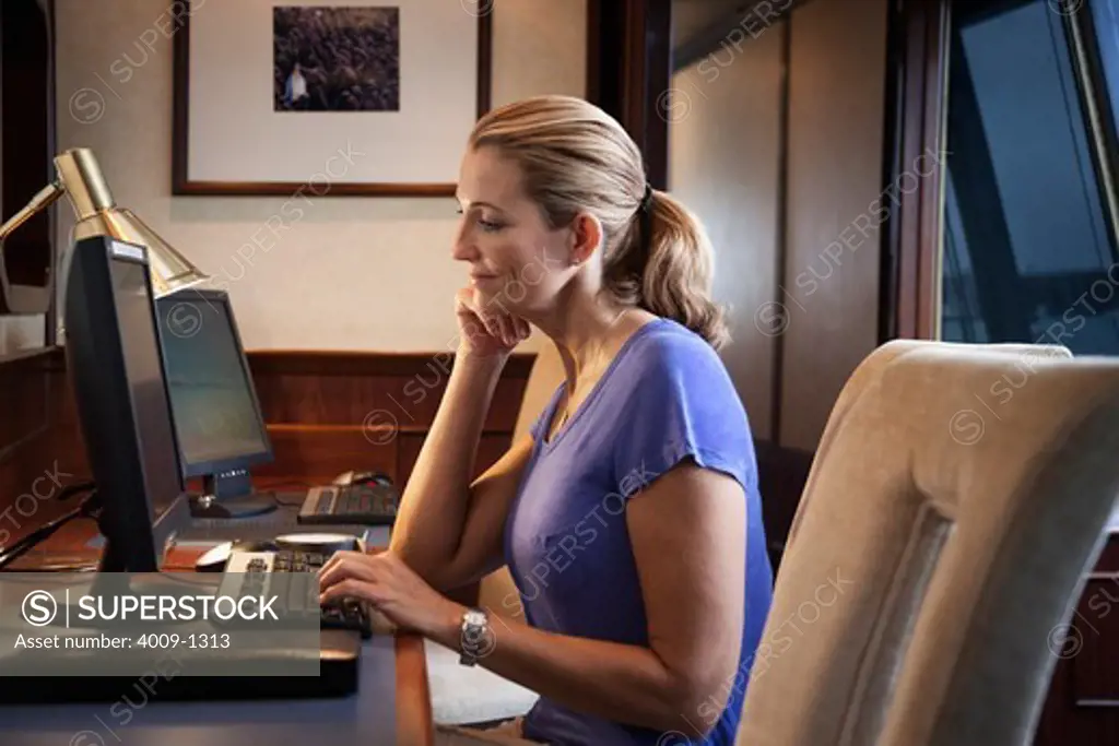 Woman using desktop computer in office on cruise ship