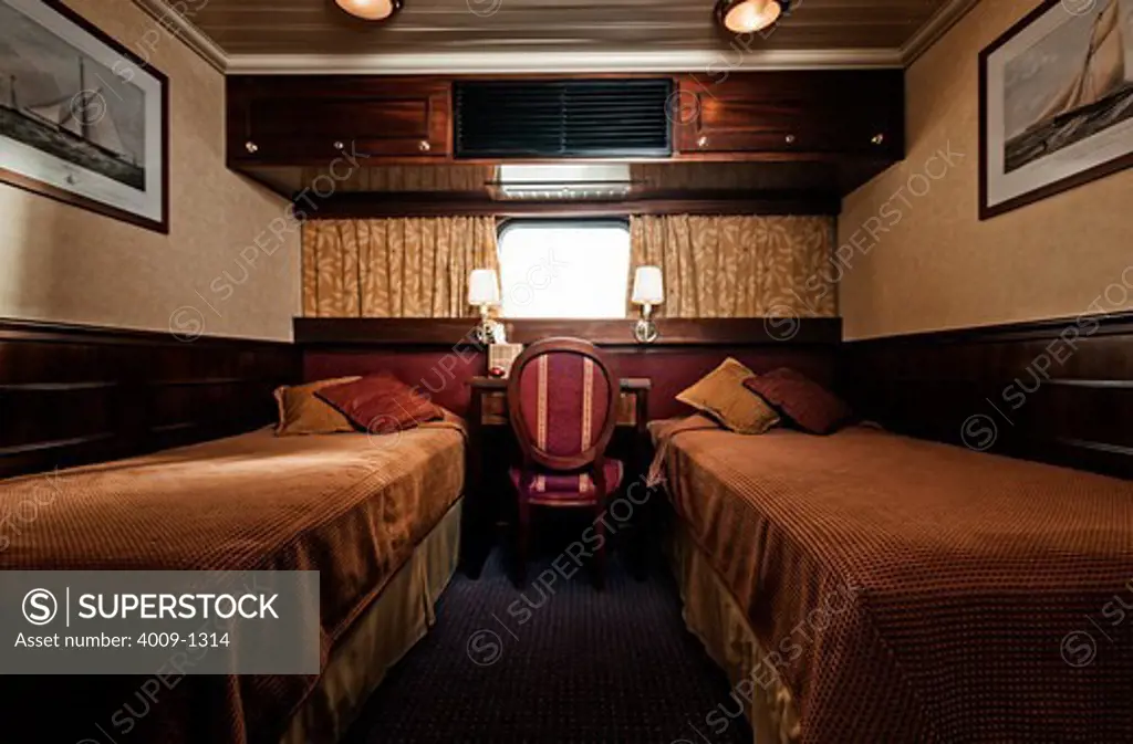 Interior of ship cabin with desk between two twin size beds