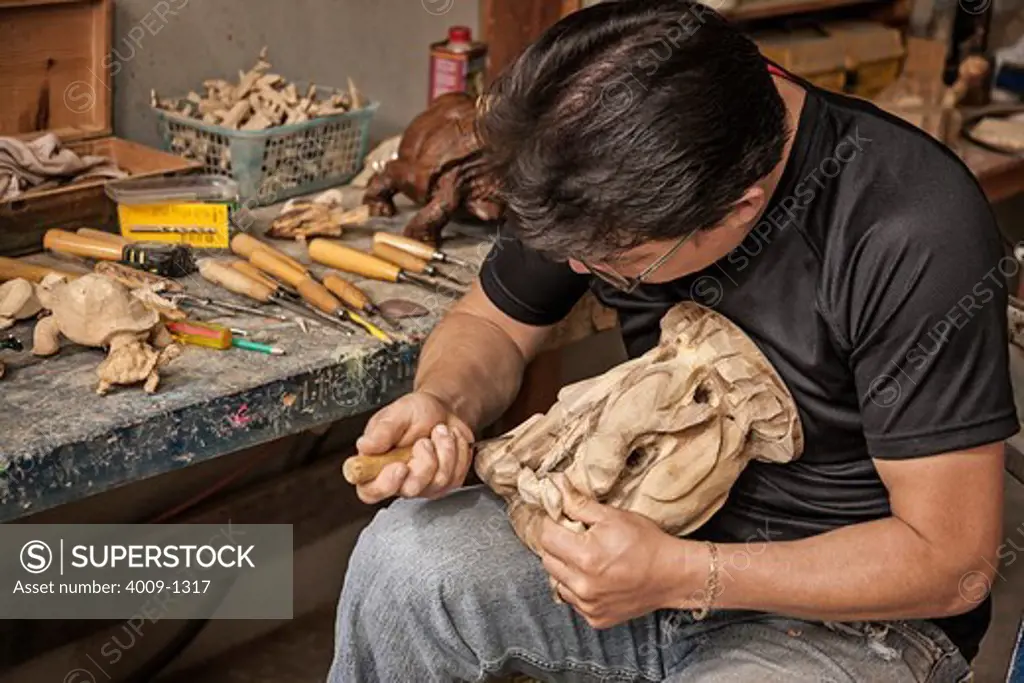 Ecuador, Galapagos Islands, Man using wood carving tool to create wood carving sculpture of animals from Ecuador, Galapagos Islands,