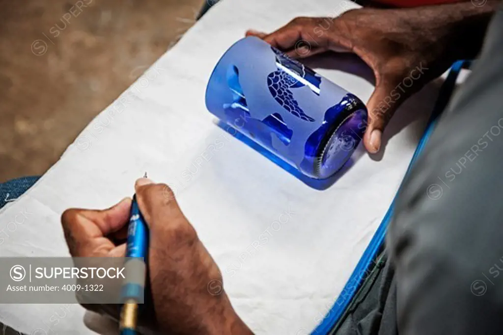 Ecuador, Galapagos Islands, Man etching design into glass bottle cup in artisan workshop