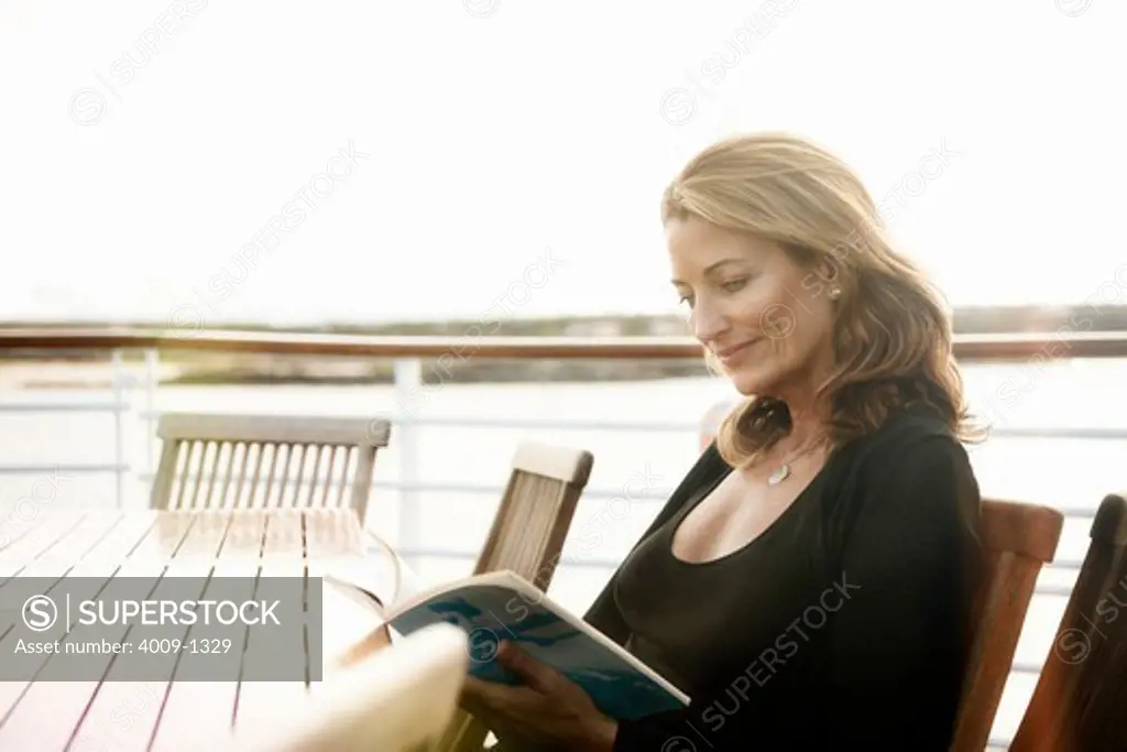 Ecuador, Galapagos Islands, Woman reading magazine while sitting at table on deck of cruise ship