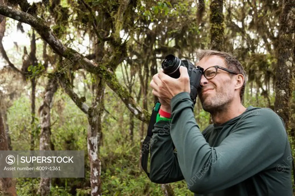 Ecuador, Galapagos Islands, Man taking pictures with digital camera on hike in jungle