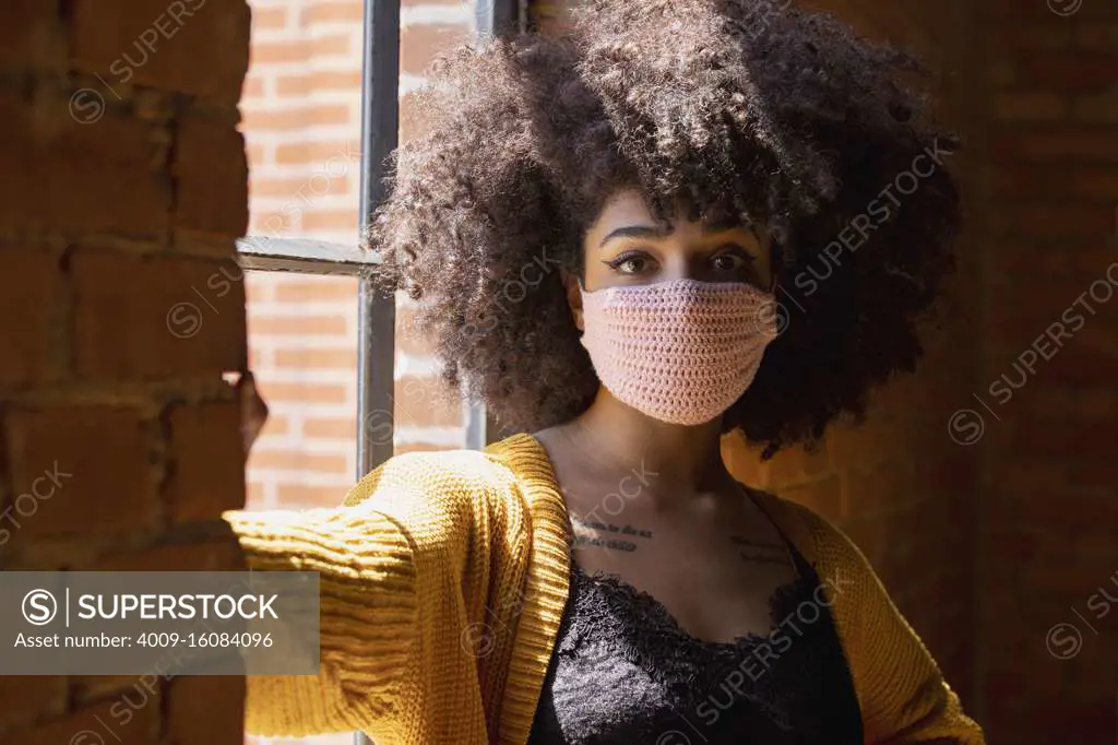 Portrait of a young African American woman with a crocheted facemask on.