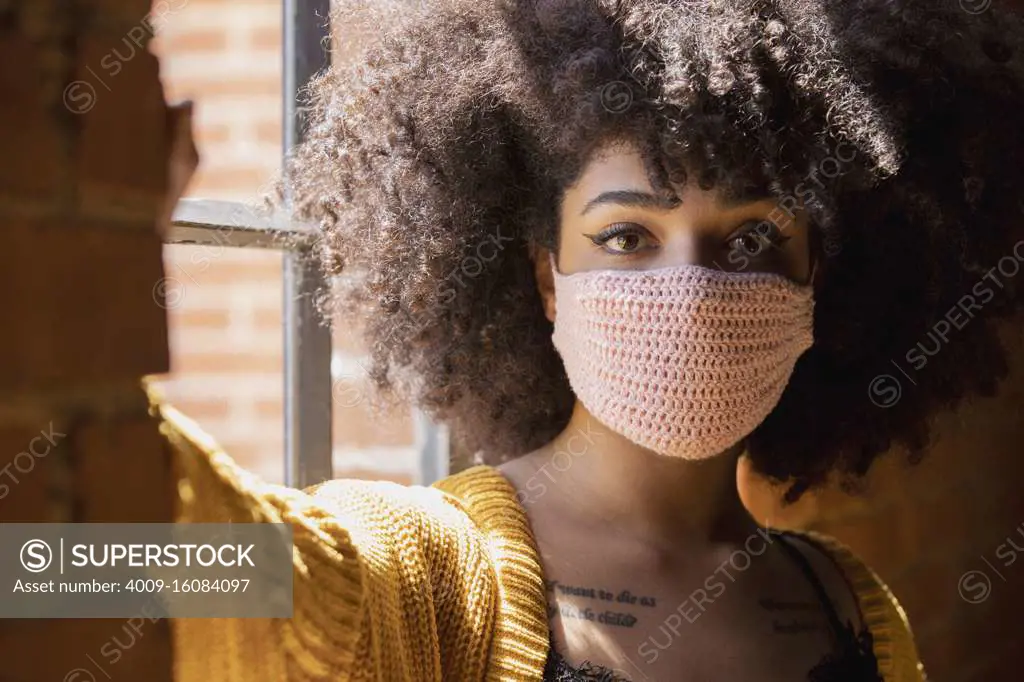 Portrait of a young African American woman with a crocheted facemask on.