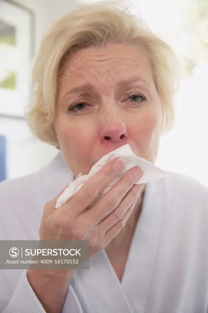 coughing senior Caucasian female sitting on side of bathtub getting ready to fill it for a bath, feeling ill using tablet to get health advice from doctor, doctors view on video call  