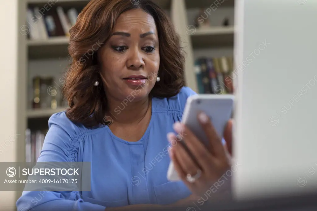 Middle aged black female doctor in home office providing telemedicine service, talking to patient on video call 