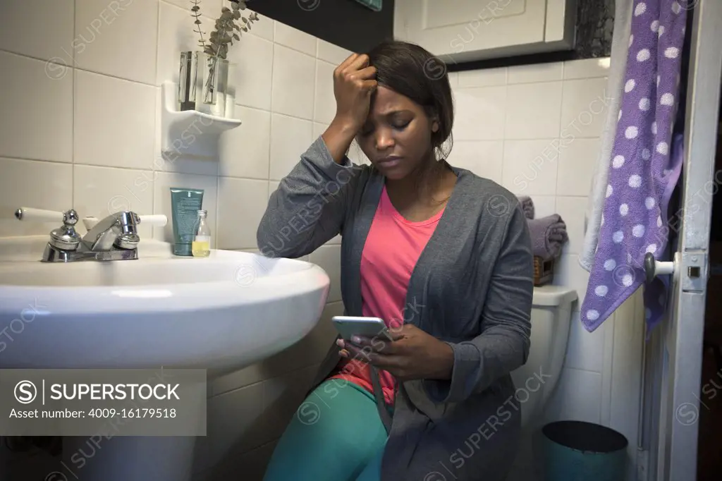 Young woman in the bathroom feeling ill using Tele-medicine to communicate with a doctor