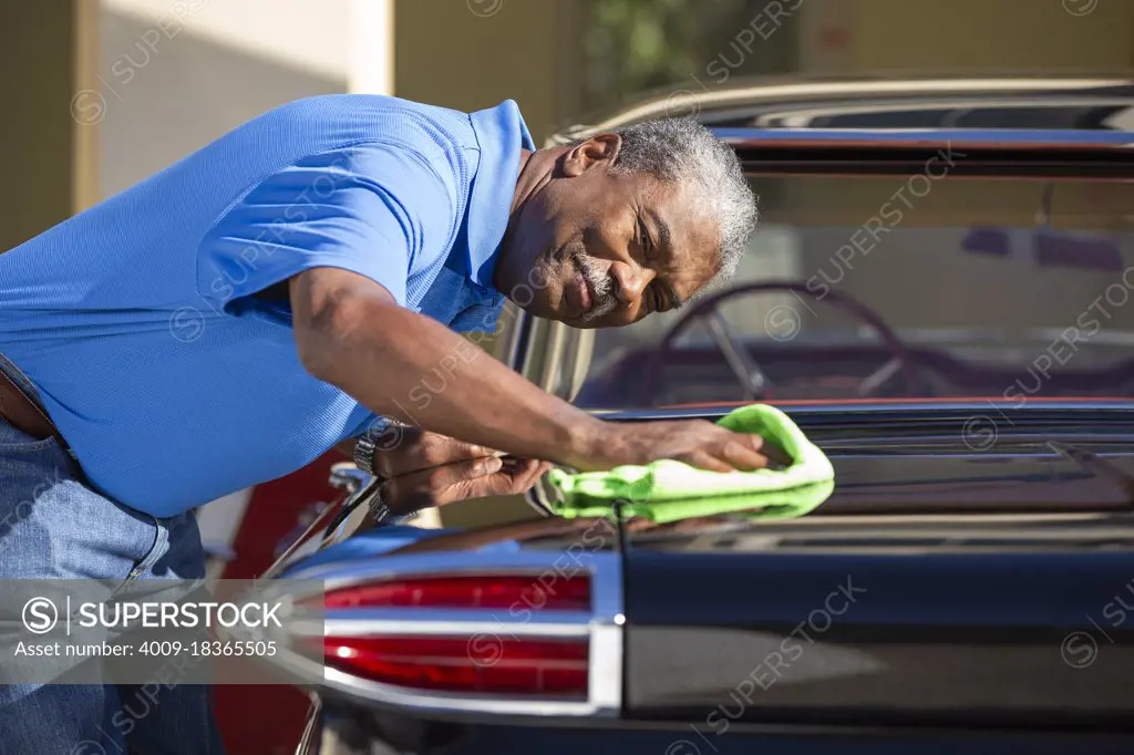 Older man drying off 1960 Oldsmobile Super 88 Holiday Sport Sedan after detailing 