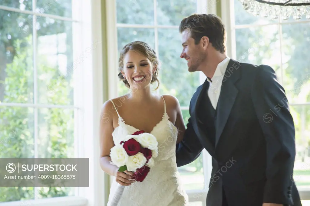 Bride and Groom walking into reception,  laughing and looking down, bride holding bouquet.