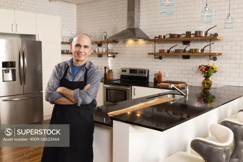 Portrait of man standing in kitchen lookin into camera with confidence. 