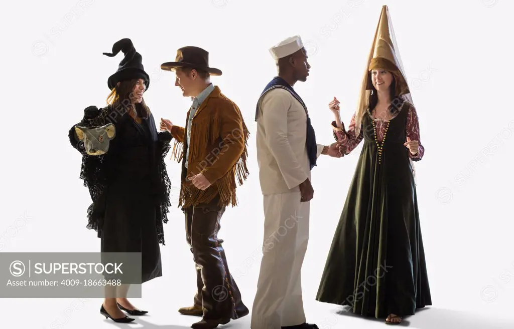 Group of four friends all dressed in Halloween costumes dancing and parting together against a white background