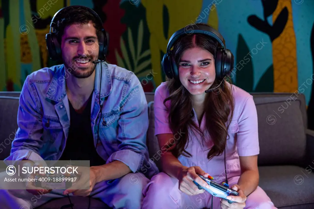 Two friends playing video games together with headsets on