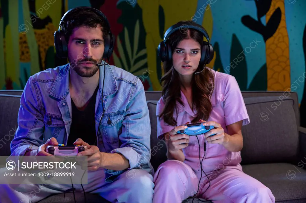 Young couple enjoying video game while sitting on sofa in living room