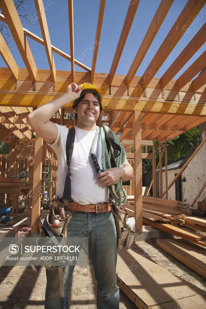 Portrait of a construction worker wearing a hard hat and a tool belt while standing on the construction site