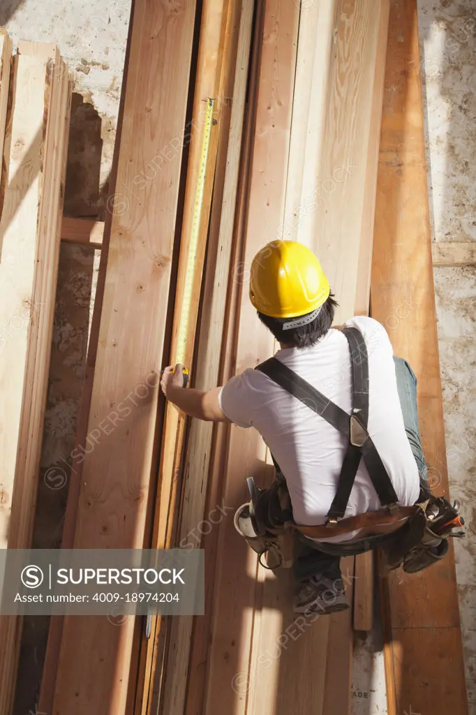 Aerial view of a man measuring wood on a residential construction site