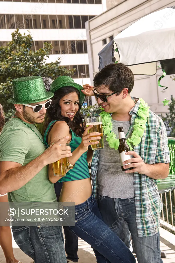 Group of three friends partying together on balcony during St Patrick's Day Parade.