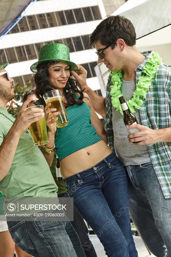 Two men flirting with one girls at the same time during St. Patrick's Day celebration. 